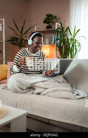 Woman working remotely from home with laptop and headphones Stock Photo