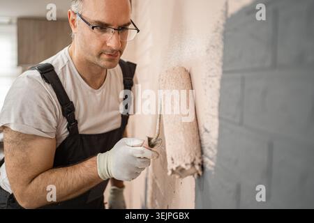 Man Painting Wall With Paint Roller Stock Photo