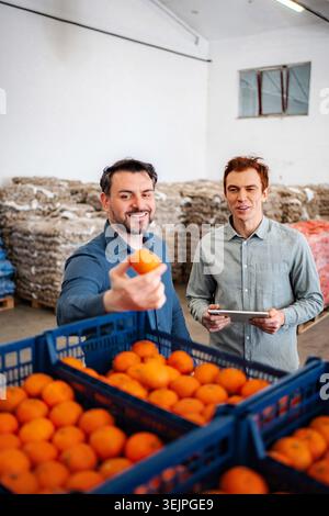 Men inspecting oranges in warehouse for quality control Stock Photo