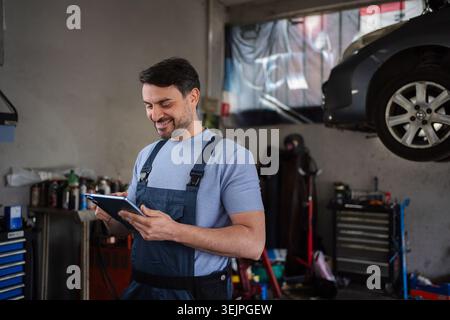 Car mechanic using a digital tablet in a repair shop Stock Photo