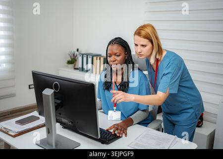 Female nurses collaborating on computer researching medical information Stock Photo