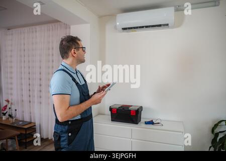 Technician checking air conditioning unit using a digital tablet for maintenance Stock Photo