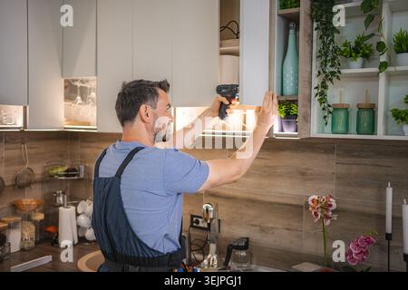 Carpenter working on a new kitchen using a cordless screwdriver Stock Photo