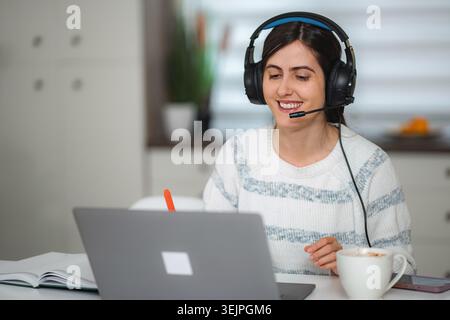 Young woman working remotely from home, participating in a video call Stock Photo