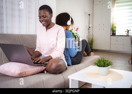 Mother working from home while her daughter is listening to music Stock Photo