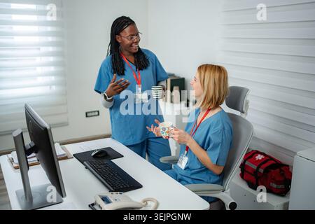 Diverse nurses collaborating and discussing in hospital office during break Stock Photo