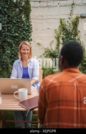 Two colleagues working outdoors in the garden using laptop Stock Photo