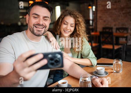 Happy couple taking a selfie while having coffee at a cafe Stock Photo