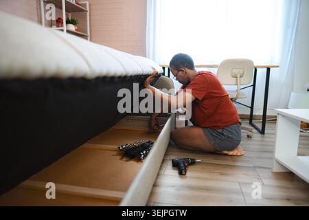 Woman assembling furniture in bedroom using a screwdriver Stock Photo