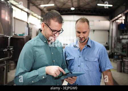 Brewery workers discussing production data on digital tablet Stock Photo