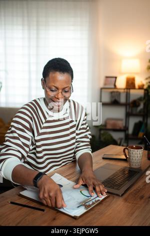Smiling woman working at home office reviewing business documents Stock Photo