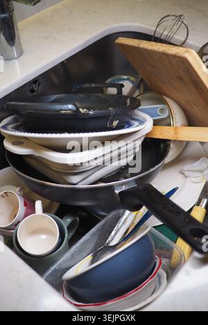 Dishes piled in a kitchen sink after cooking a meal Stock Photo