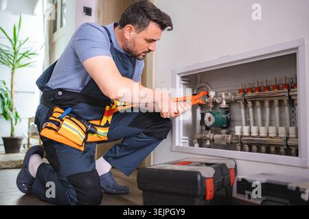 Plumber Installing Underfloor Heating Manifold in a Residential Building Stock Photo