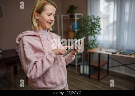 Woman smiling using digital tablet at home Stock Photo