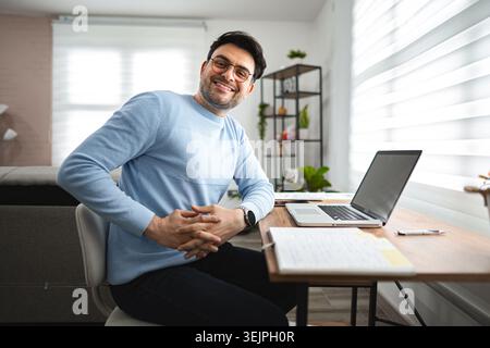 Portrait of smiling man at desk and laptop Stock Photo
