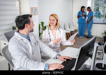 Medical professionals collaborating in hospital office discussing patient data Stock Photo