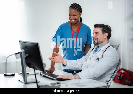 Doctors and nurses collaborating in medical office using computer Stock Photo