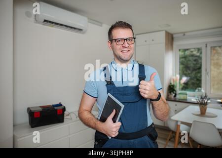 Repairman giving thumbs up after checking air conditioner Stock Photo