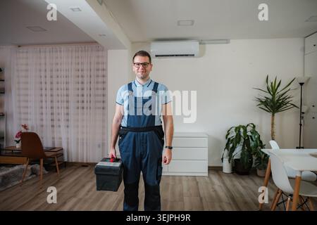 Technician holding toolbox standing in living room Stock Photo
