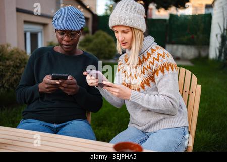 Women friends using smartphones outdoors on autumn evening Stock Photo