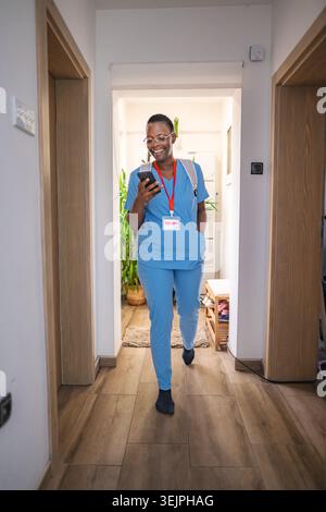 Smiling female doctor walking in the corridor and using smartphone Stock Photo