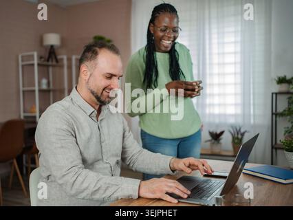 Diverse couple working from home with laptop Stock Photo