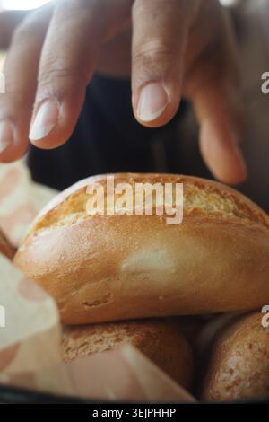 Person reaches for a bread roll in a basket Stock Photo