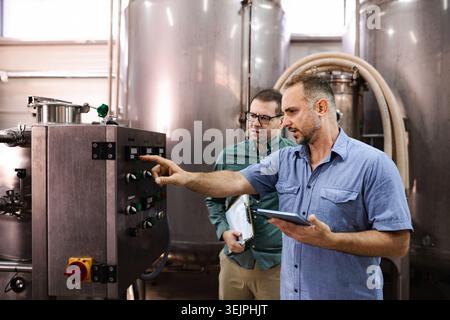 Men operating industrial control panel in brewery factory Stock Photo