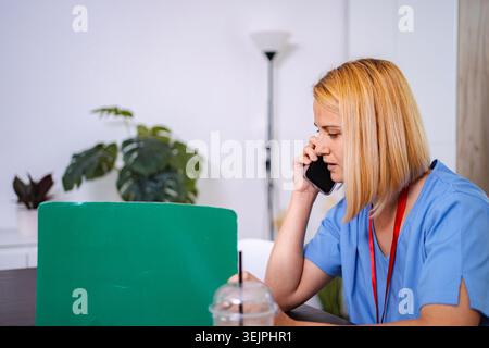 Female doctor talking on the phone and taking notes at home Stock Photo