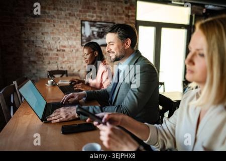 Diverse business professionals working together on laptops in coworking space Stock Photo