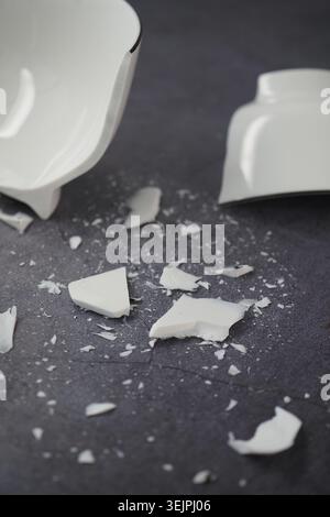 Broken white ceramic bowl lies on a dark surface Stock Photo