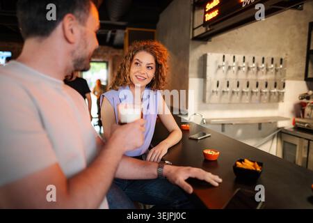 Couple enjoying drinks and conversation at a bar counter Stock Photo