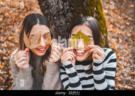 Two Young Women Holding Leaves in Front of Their Eyes Stock Photo