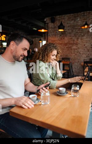 Young Couple Working on Laptop and Smartphone in Cafe Stock Photo