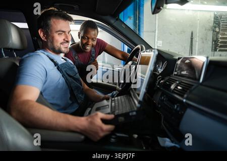 Mechanics performing diagnostics on a car's electronics using a computer Stock Photo