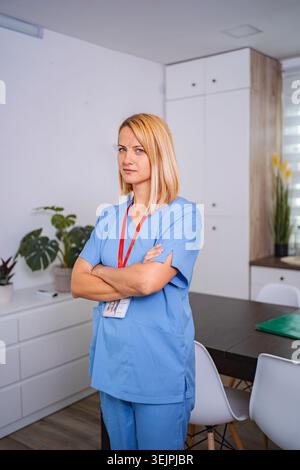 Confident female doctor posing with arms crossed in medical office Stock Photo
