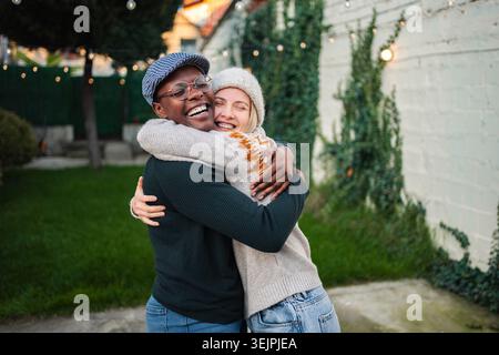 Happy young adult multi-ethnic couple embracing and smiling outdoors Stock Photo