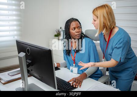 Nurses collaborating on computer work in hospital office Stock Photo