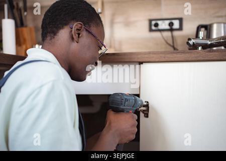 Handyman Installing Kitchen Cabinet Using Cordless Drill Stock Photo