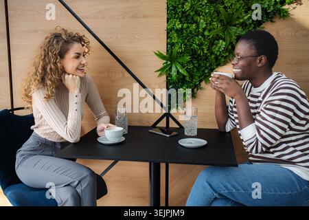 Diverse female friends enjoying coffee shop conversation, laughing Stock Photo