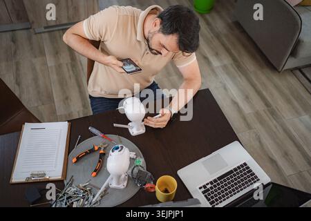 Man installing security camera at home using smartphone app Stock Photo