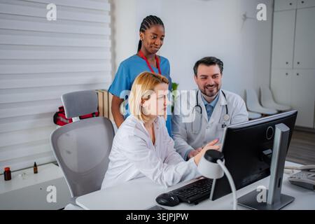 Diverse medical professionals collaborating on patient data using a computer Stock Photo