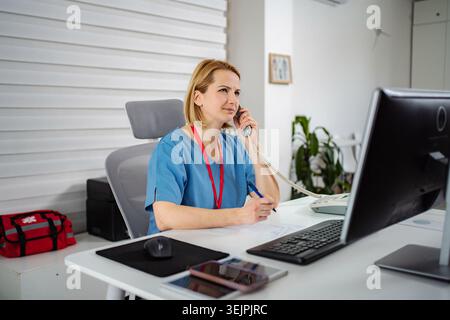 Healthcare worker talking on phone registering appointments at clinic Stock Photo