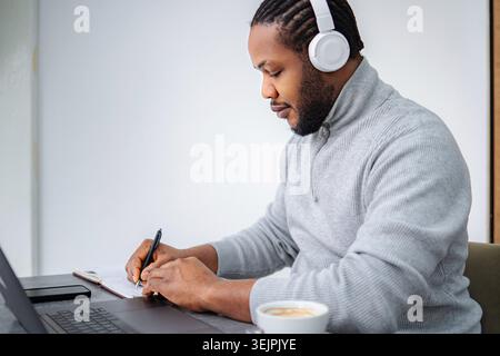 Black entrepreneur working remotely from home with headphones Stock Photo