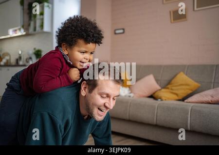 Father son playing piggyback at home together Stock Photo