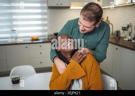 Interracial couple sharing happy morning moment in kitchen Stock Photo