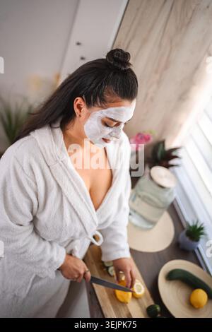 Young woman preparing detox water with a facial mask Stock Photo