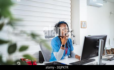 Mid adult woman yawning while working at her office desk in healthcare Stock Photo