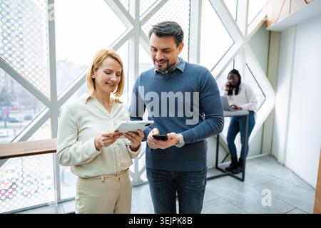Coworkers collaborating on digital tablet in modern office Stock Photo