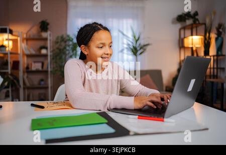 Schoolgirl doing online education or homework remotely at home on a laptop Stock Photo